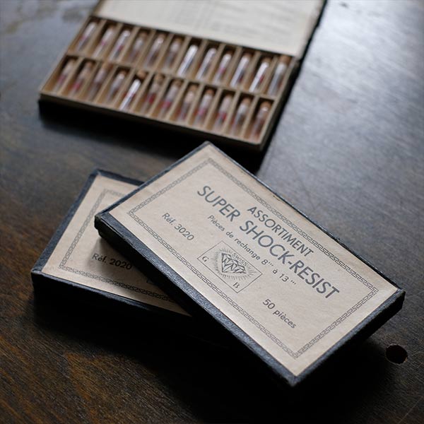 A set of small jars containing mechanical watch parts