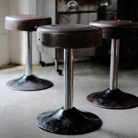 A swivel stool with rusty iron legs